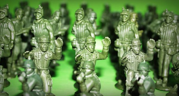 Green plastic soldiers standing close together on a green surface.