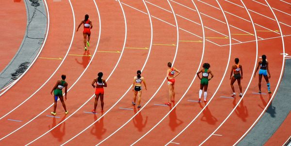 Runners lined up to race on a running track and one runner has gone ahead in false start.
