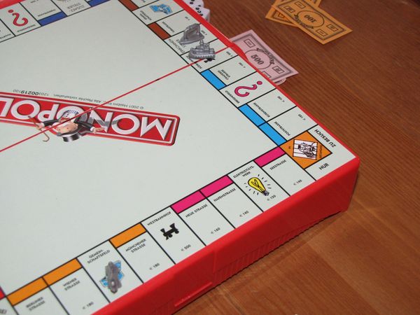 A corner of the board game monopoly on a table.