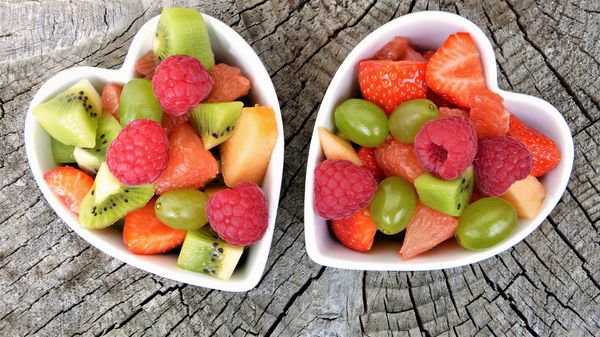 Two heart shaped bowls filled with colorful fruits