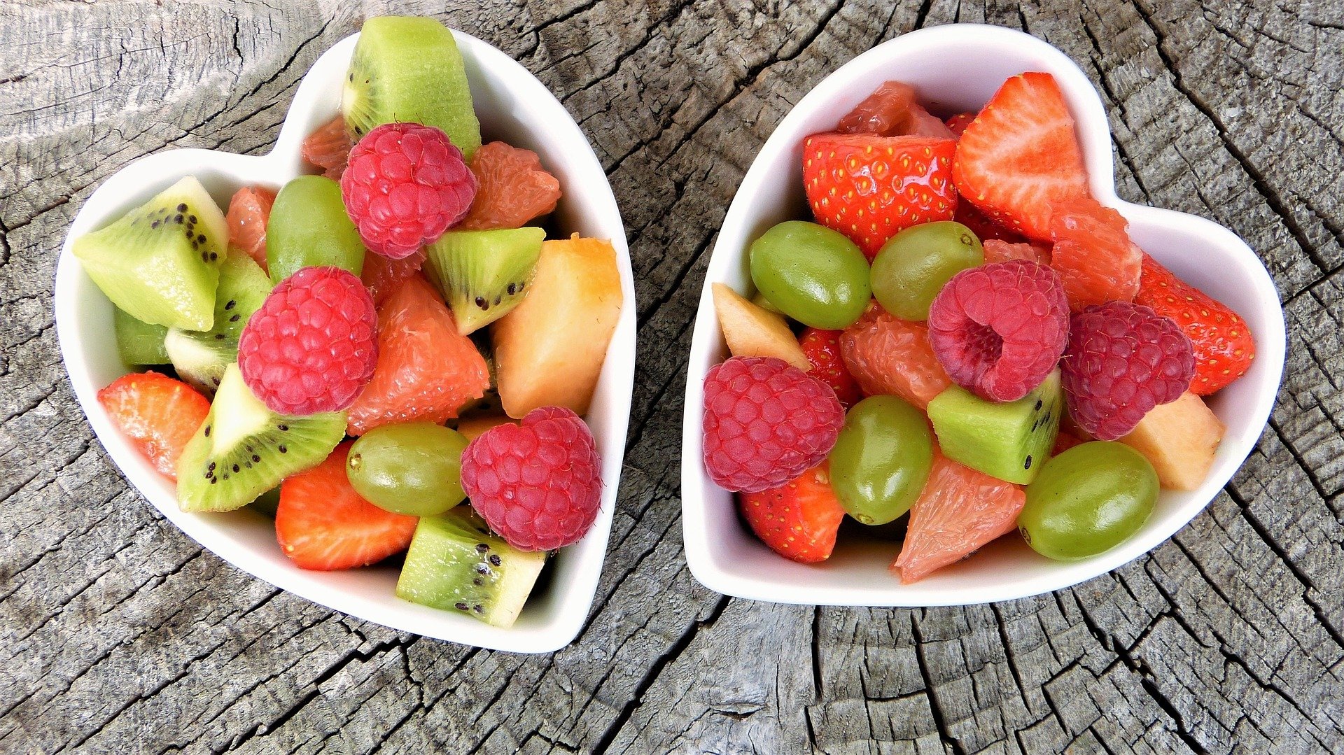 two heart shaped bowls filled with colorful fruits