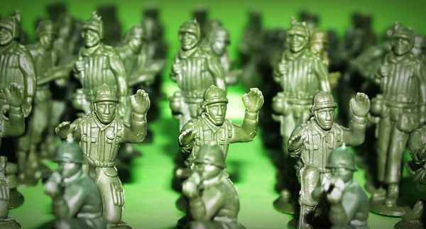 Green plastic soldiers standing close together on a green surface.