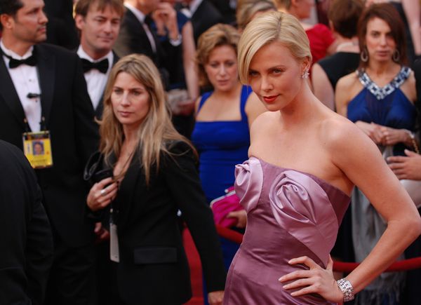 Hollywood actress Charlize Theron in a purple dress is posing for cameras on the red carpet.