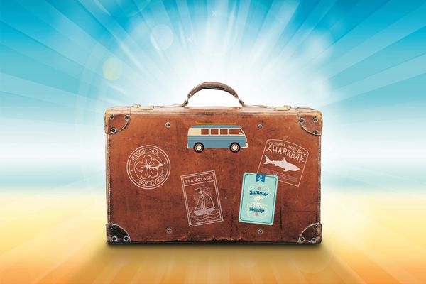 A travel-worn suitcase backlit by the sun.