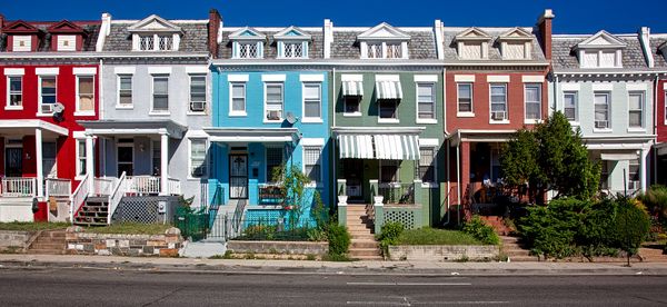 A row of connected and different-colored houses.