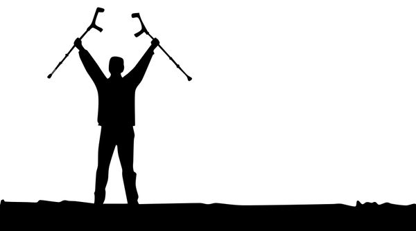 A silhouette of a man holding up his crutches as if he is suddenly able to walk.