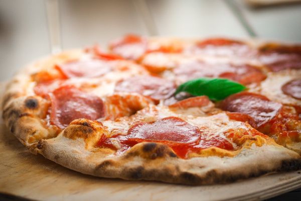 A pizza with salami and a leaf on top.