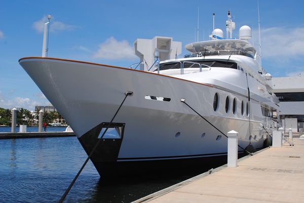 A large white yacht moored at a dock.