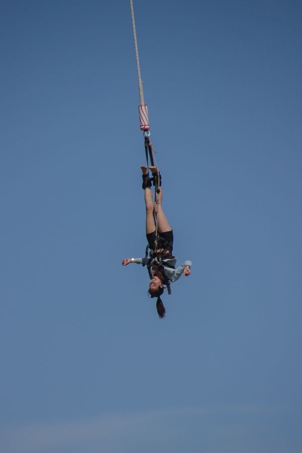 A woman hanging upside down on a bungy cord.