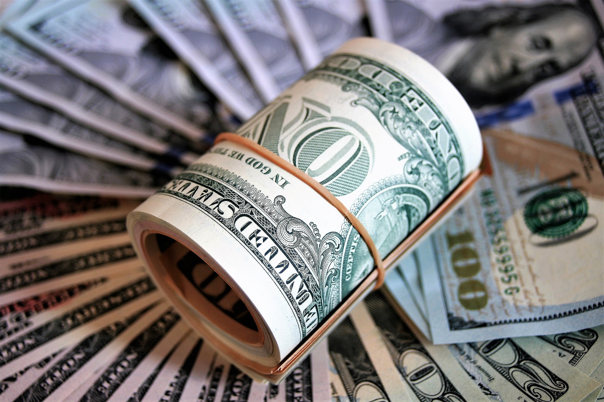 a roll of cash on a pile of cash
